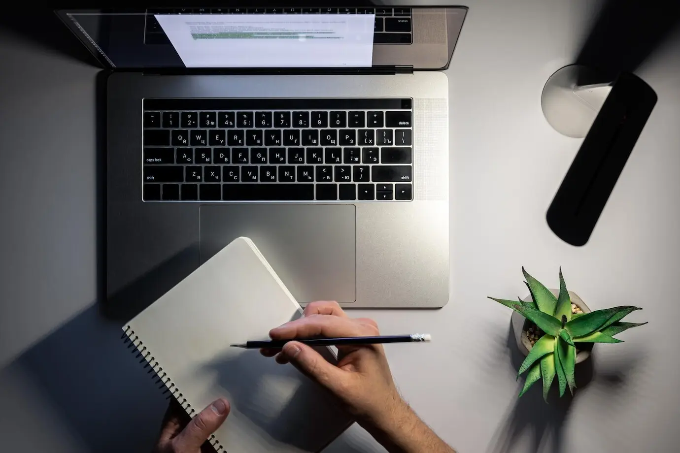 Draufsicht auf Laptop und Lampe bei nächtlicher Arbeit.